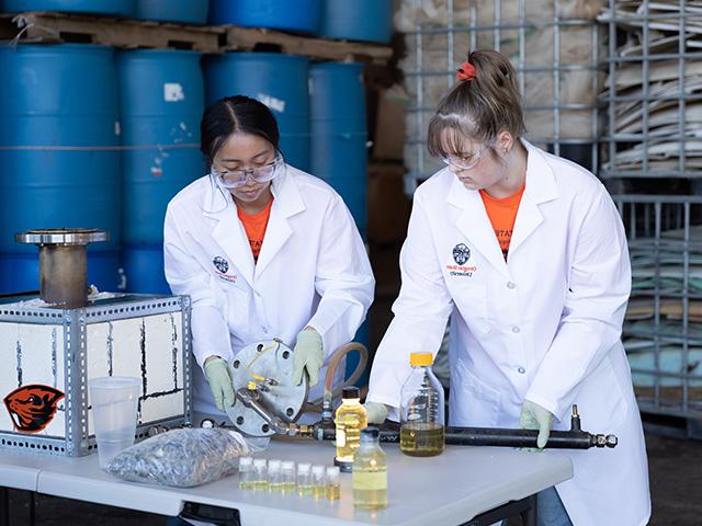 two researcher in lab coat examine experiment equipment with glowing vials of liquid