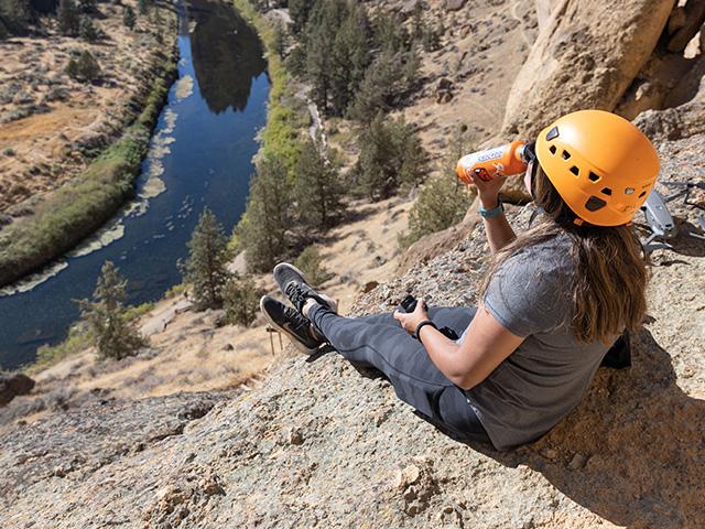 rock climber drinking water at peak overlooking river